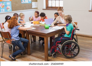 Pretty teacher helping pupils in classroom at the elementary school - Powered by Shutterstock