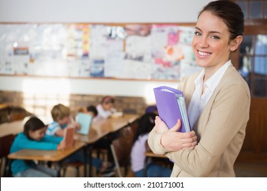 Pretty teacher smiling at camera at back of classroom at the elementary school - Shutterstock ID 210171001