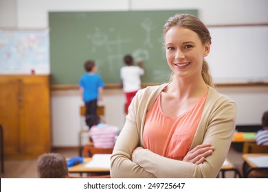 Pretty teacher smiling at camera at back of classroom at the elementary school - Shutterstock ID 249725647