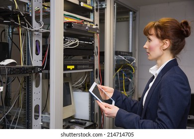 Pretty technician using tablet pc while looking at server in large data center