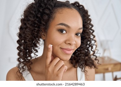 Pretty Teenage African American Girl Applying Cream On Face Looking At Camera. Young Facial Cosmetic Skin Care Concept, Natural Beauty Acne Treatment.