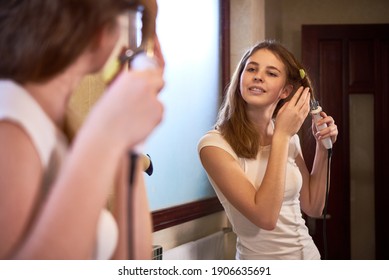 Pretty Teenage Girl Getting Ready In Bathroom And Curling Hair In Front Of Mirror