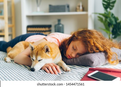 Pretty Teenage Girl Is Sleeping At Home Hugging Adorable Shiba Inu Dog In Sleep Lying On Couch In Apartment. Lifestyle, Relaxation And Animals Concept.