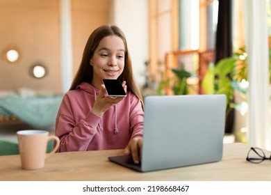 Pretty Teenage Girl Using Laptop And Talking On Speakerphone, Dictating Voice Message, Using Online Translator App Or Voice Recognition Software, Sitting At Desk At Home