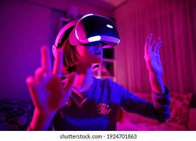 Pretty teenage girl wearing virtual reality headset in a dark room. Cute teen using VR glasses to play a game. Child in virtual augmented reality helmet. Future technology concept. - Powered by Shutterstock