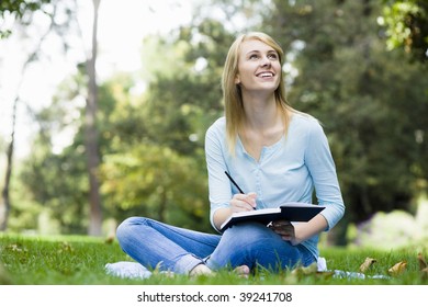 Pretty Teenage Girl Writing In Journal In Park