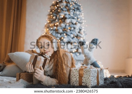 Pretty teenager girl in scandinavian christmas interior with gif box sitting on the woollen plaid