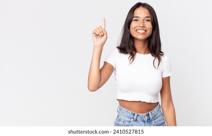 pretty thin hispanic woman smiling cheerfully and happily, pointing upwards - Powered by Shutterstock