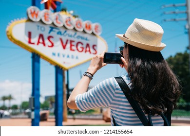 pretty tourist taking photo of the Las Vegas city sign by cellphone. young lady traveler shooting the famous landmark in Nevada. backpacker in las vegas trips concept.