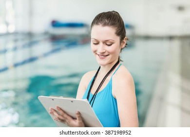 Pretty trainer taking notes at the pool