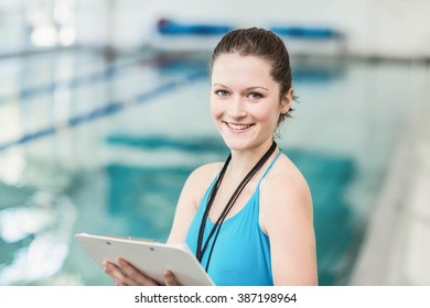 Pretty trainer taking notes at the pool - Powered by Shutterstock