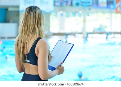 Pretty trainer taking notes at the pool