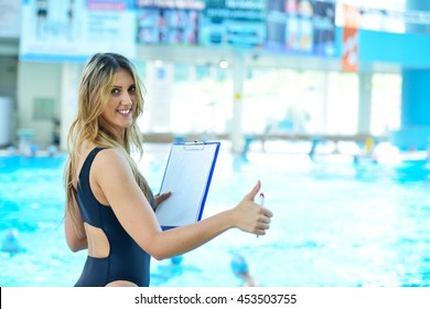 Pretty trainer taking notes at the pool
