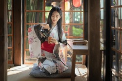 Pretty The Traveller Young Asian Woman Wearing A Japanese Traditional Kimono Dress, A Yukata Dress, And Holding An Umbrella Is Happy And Cheerful In The Green Natural Park. Japanese Traditional Dress.