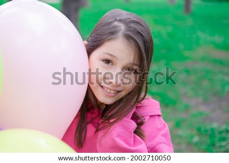 pretty tween teenager brunette girl in pink holding colorful hot air balloons outdoors. party, birthday concept. summertime. happy children. hollidays, summer break.