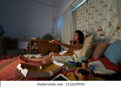 Pretty Vietnamese College Student Eating Snacks And Watching Tv Late At Night