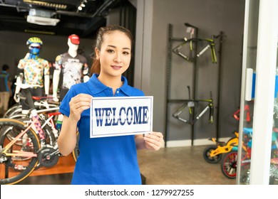 Pretty Vietnamese Sports Store Manager Holding Welcome Sign