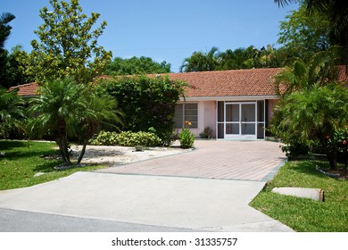 Pretty View Of An Average One Level Home In South West Florida, Surrounded By Tropical Trees And Plants.