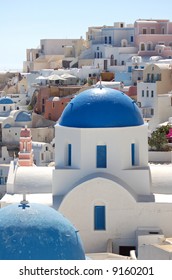 A pretty view of whitewashed and colorful buildings in the Santorini cliff town of Oia.