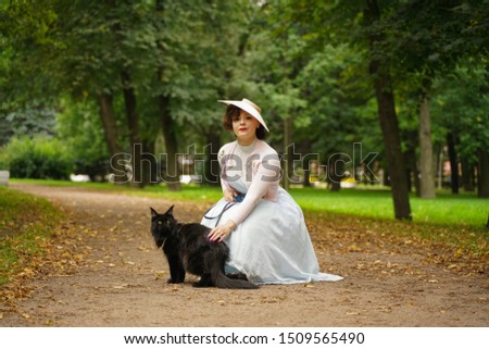 Pretty vintage woman walking with her black cat maine coon in the park