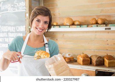 Pretty waitress picking up croissant at the coffee shop - Powered by Shutterstock