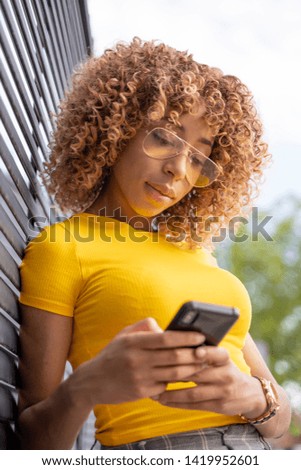 Similar – Serious black woman with afro hair looking at her smart phone outdoors.