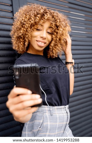 Similar – Serious black woman with afro hair looking at her smart phone outdoors.