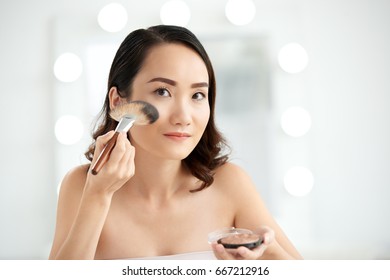 Pretty Woman Applying Highlighter On Highest Points Of Her Cheeks