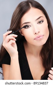 pretty woman applying mascara on her lashes