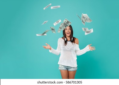 Pretty Woman in beachwear throws the money in studio. Isolated turquoise background