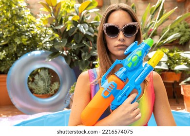 A Pretty Woman In Bikini With A Water Pistol In A Paddling Pool