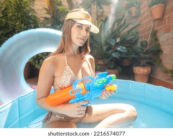 A Pretty Woman In Bikini With A Water Pistol In A Paddling Pool