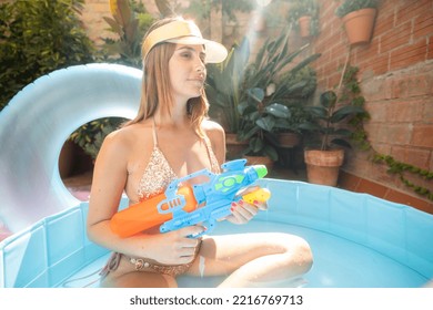 A Pretty Woman In Bikini With A Water Pistol In A Paddling Pool