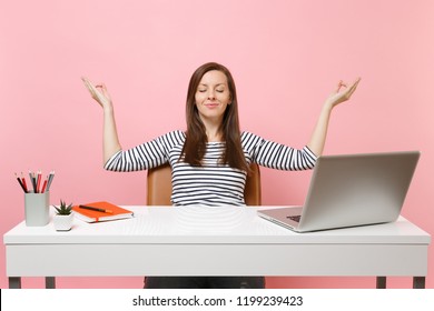 Pretty Woman With Closed Eyes Meditation Spread Hands In Yoga Pose Sit After Work At White Desk With Contemporary Pc Laptop Isolated On Pastel Pink Background. Achievement Business Career. Copy Space