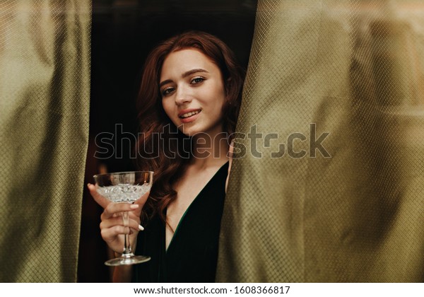 Pretty
woman in dark green outfit holds martini
glass