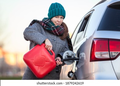 Pretty woman a driver trying to pour diesel in tank of her suv from plastic can, an accident on the road at winter season - Powered by Shutterstock