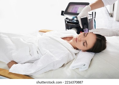 Pretty woman enjoying radiofrequency lifting procedure for her face skin rejuvenation at cosmetology. RF lifting