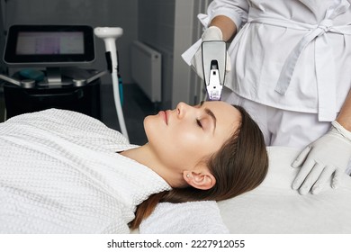 Pretty woman enjoying radiofrequency lifting procedure for her face and forehead skin rejuvenation in aesthetic cosmetology. RF lifting