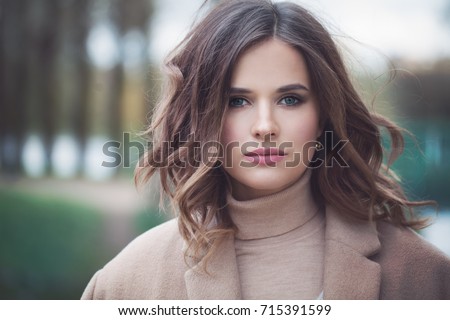 Pretty Woman Fashion Model with Blowing Curly Hair. Cute Girl Outdoors