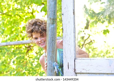 Pretty Woman In A Garden And A Dress Peeking Around A Fence Post.