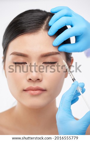 Pretty woman getting  injections to lift her eyebrowns and look younger