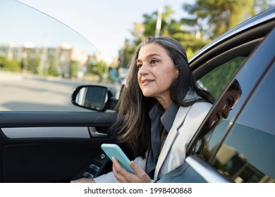 Pretty Woman Getting Out Of The Car With Smartphone In Hand