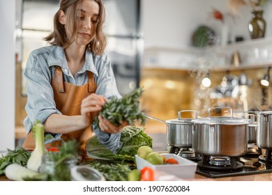 Pretty Woman With Green Ingredients And Spicy Herbs Cooking Healthy Food On The Kitchen. Healthy And Wellness Concept. High Quality Photo