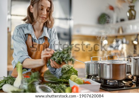 Pretty woman with green ingredients and spicy herbs cooking healthy food on the kitchen. Healthy and wellness concept. High quality photo