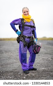 Pretty Woman Happy, Dressed In Jumpsuit And Parachute Harness On Airport Runway Ready For Skydive Jump