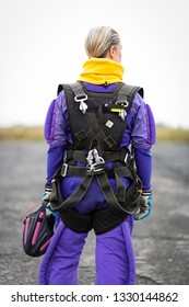 Pretty Woman Happy, Dressed In Jumpsuit And Parachute Harness On Airport Runway Ready For Skydive Jump