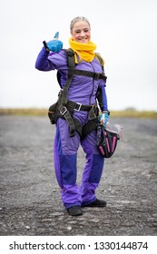 Pretty Woman Happy, Dressed In Jumpsuit And Parachute Harness On Airport Runway Ready For Skydive Jump