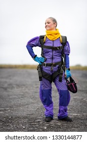 Pretty Woman Happy, Dressed In Jumpsuit And Parachute Harness On Airport Runway Ready For Skydive Jump