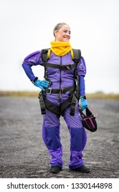 Pretty Woman Happy, Dressed In Jumpsuit And Parachute Harness On Airport Runway Ready For Skydive Jump