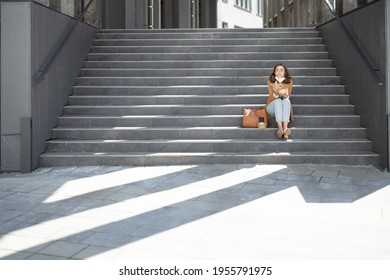 Pretty Woman Have Outdoor Lunch Near Office Building While Sitting On The Stairs. Healthy Meal For Takeaway. With Lowered Protective Mask On Her Chin And Social Distance Alone. Copy Space.